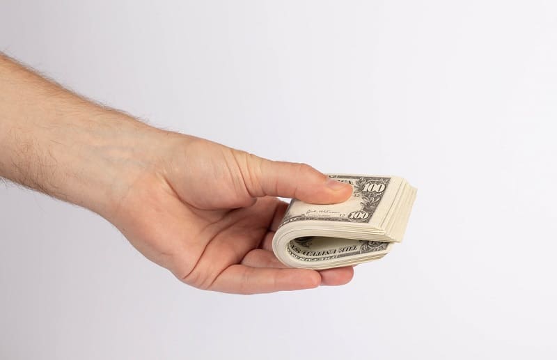 Hand holding stack of dollar bills